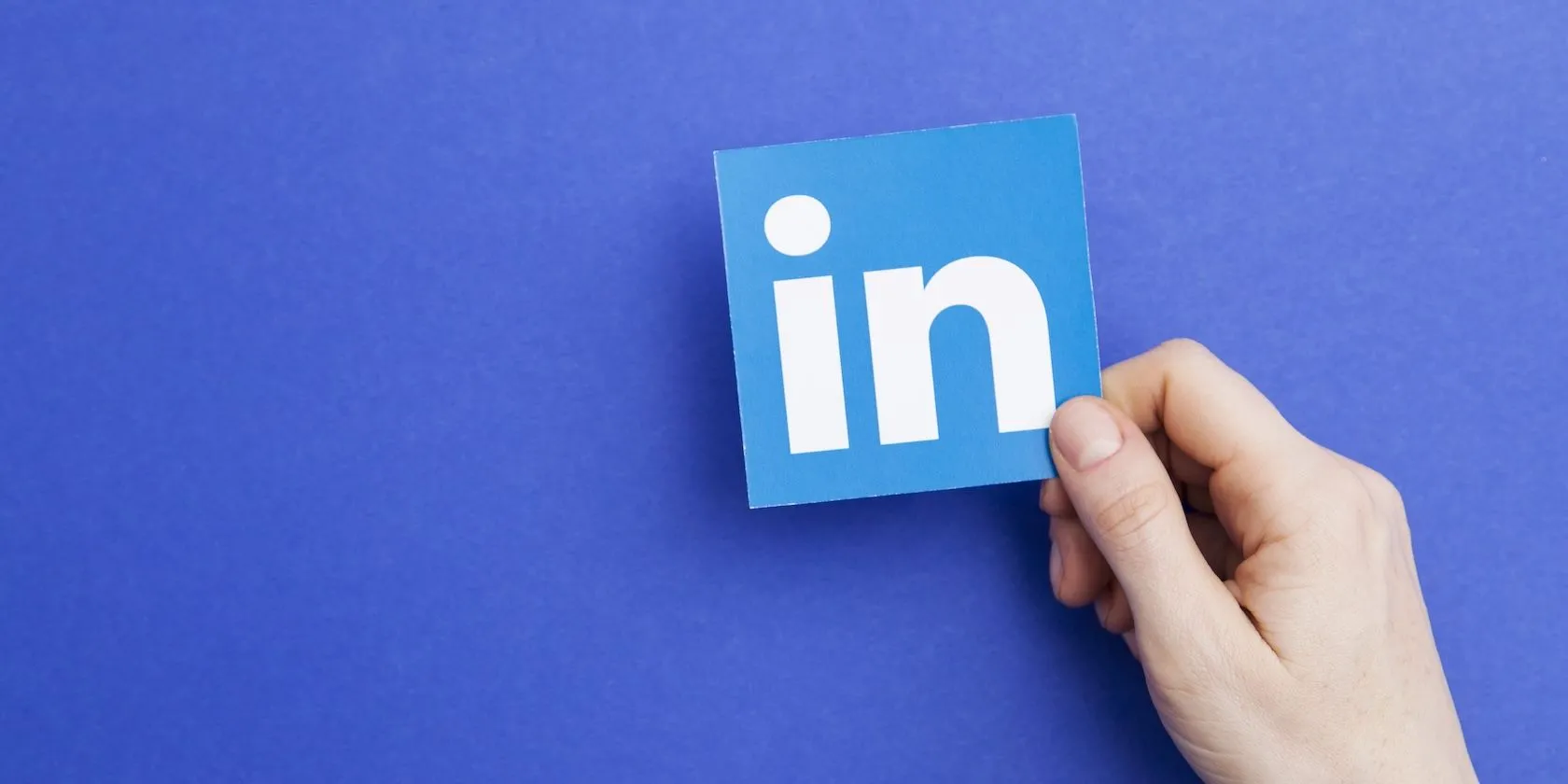 Biểu tượng LinkedIn được giữ trong tay, đại diện cho mạng xã hội chuyên nghiệp thu thập dữ liệu người dùng để đào tạo AI.