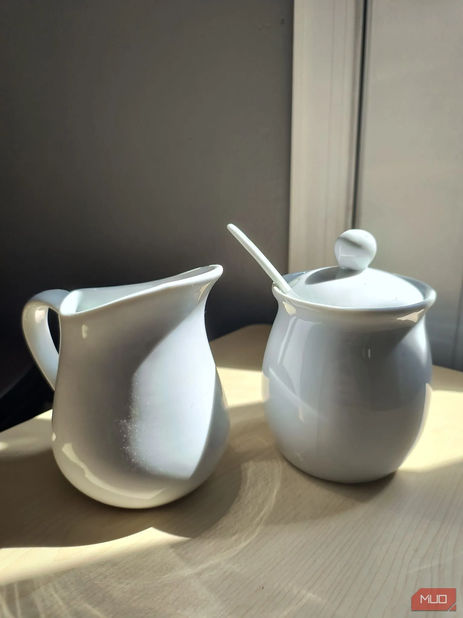 Bộ chén đường và sữa bằng gốm trắng đặt dưới ánh nắng trực tiếp, ảnh được chụp với HDR.
