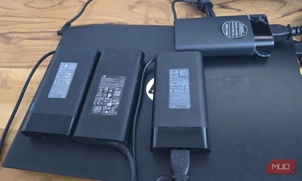 Bốn bộ sạc 150W của HP xếp trên một chiếc laptop HP, biểu tượng cho chi phí và sự bất tiện khi sạc độc quyền bị hỏng.