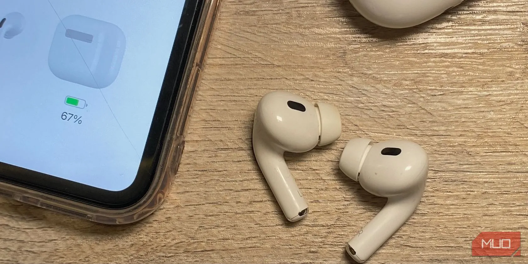 Các thế hệ tai nghe AirPods thường đặt cạnh iPhone trên bàn gỗ, minh họa sự khác biệt về chiều dài thân