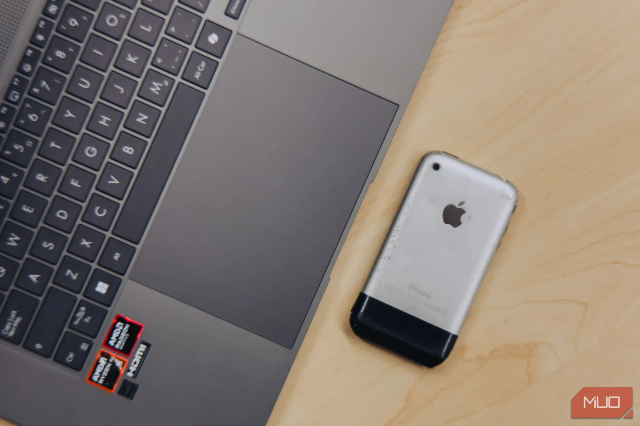 Cận cảnh trackpad lớn của ASUS Zenbook S 16 đặt cạnh iPhone 2G