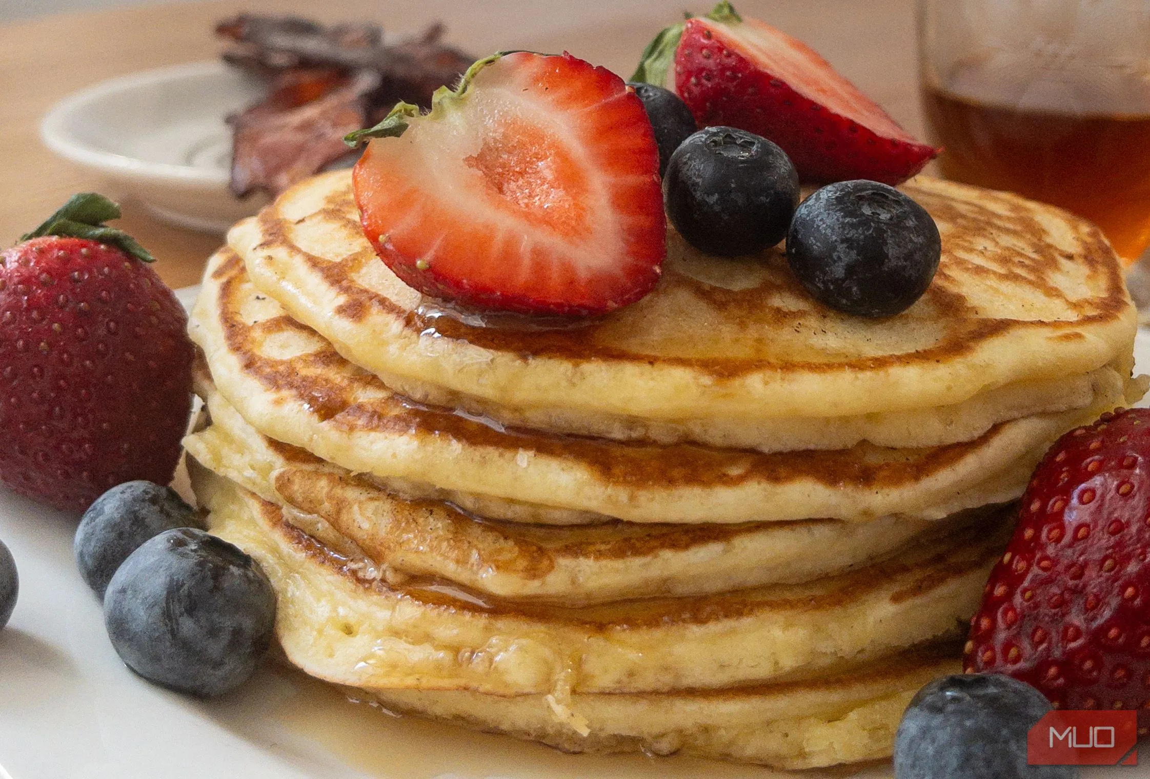 Chồng bánh pancake với siro chảy xuống, chụp từ góc 45 độ tôn lên độ cao và lớp bánh