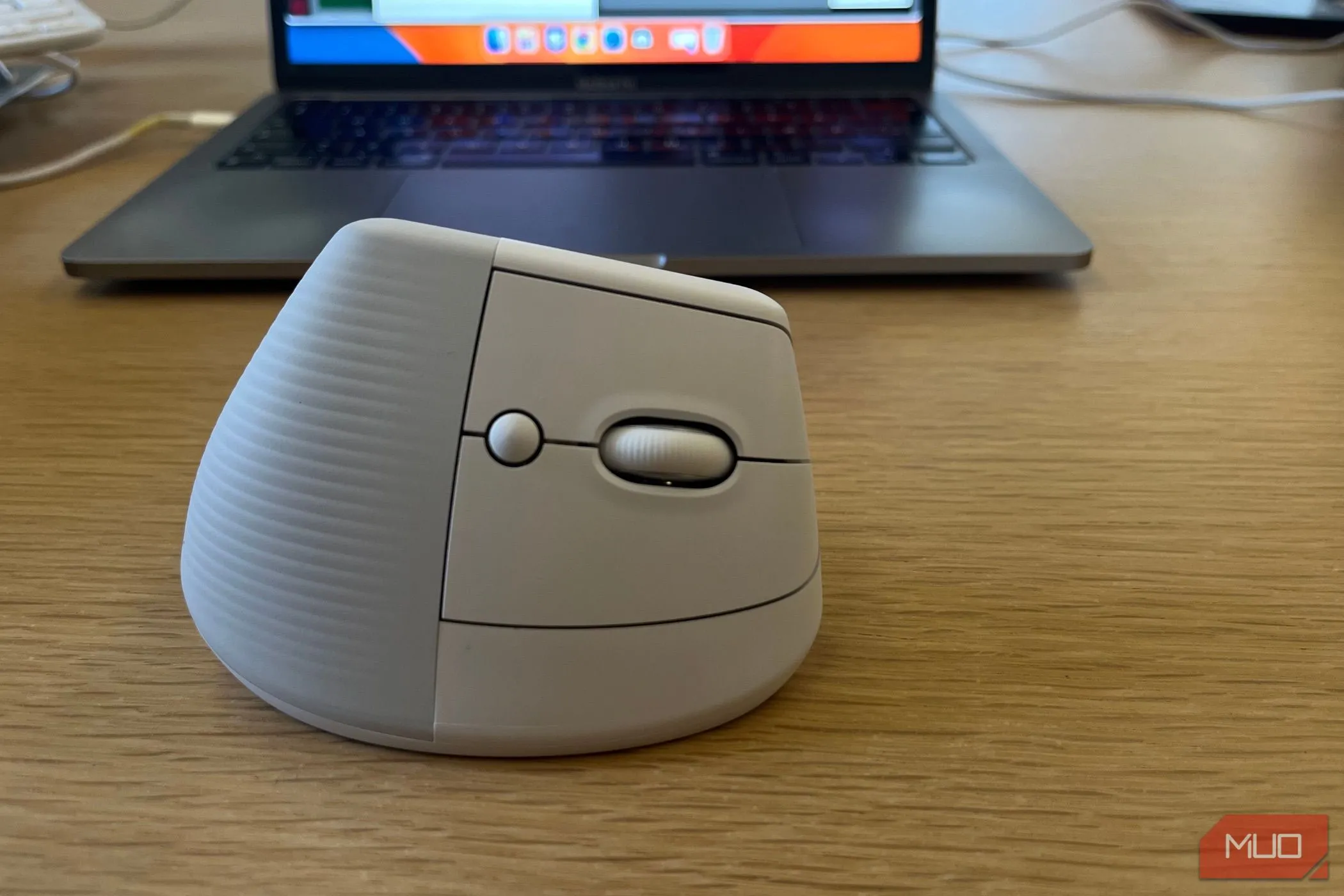 Chuột không dây Logitech Lift được đặt gần laptop trên bàn làm việc, làm nổi bật thiết kế tiện dụng.