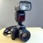 Đèn flash Godox V860II gắn trên máy ảnh chuyên nghiệp màu đen, thể hiện khả năng linh hoạt trong nhiếp ảnh