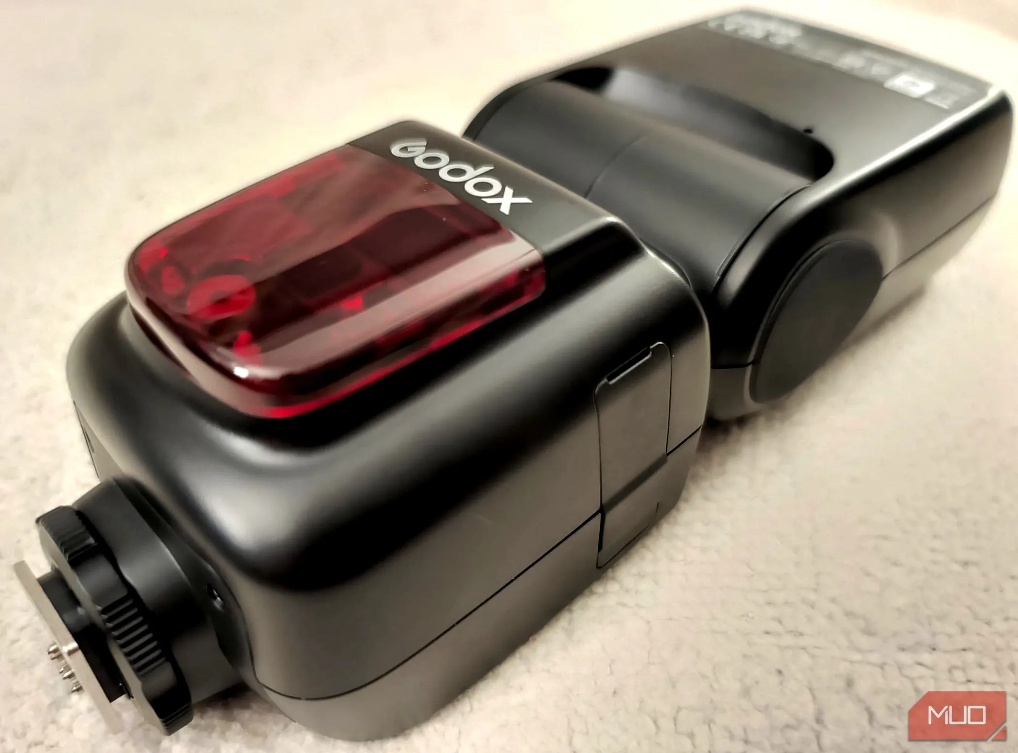 Đèn flash máy ảnh rời Godox V860II-C màu đen nằm trên một chiếc chăn màu be, cho thấy thiết kế chắc chắn và dễ dàng mang theo