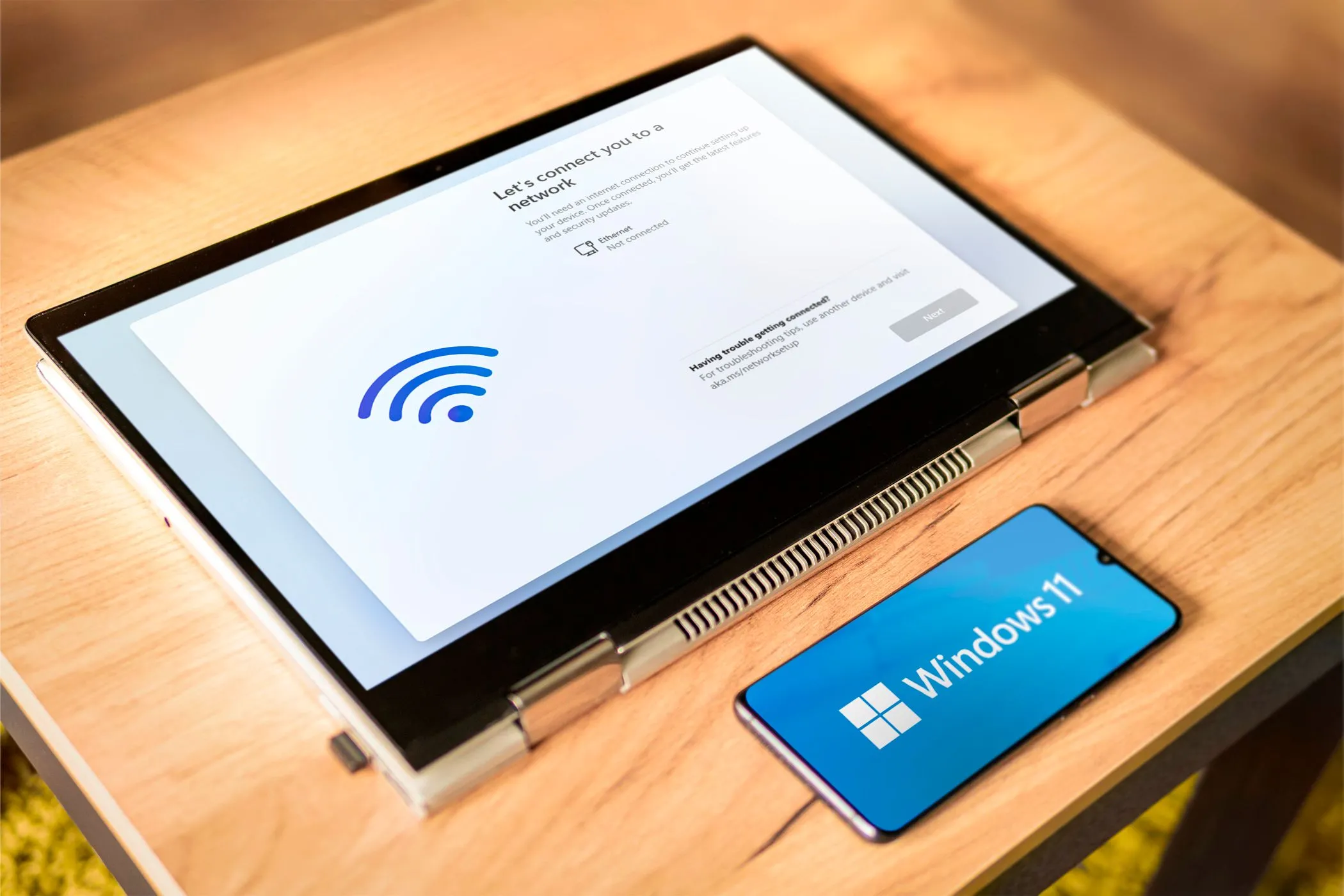 Điện thoại Android hiển thị logo Windows 11 bên cạnh máy tính xách tay, tượng trưng cho khả năng điều khiển PC từ xa
