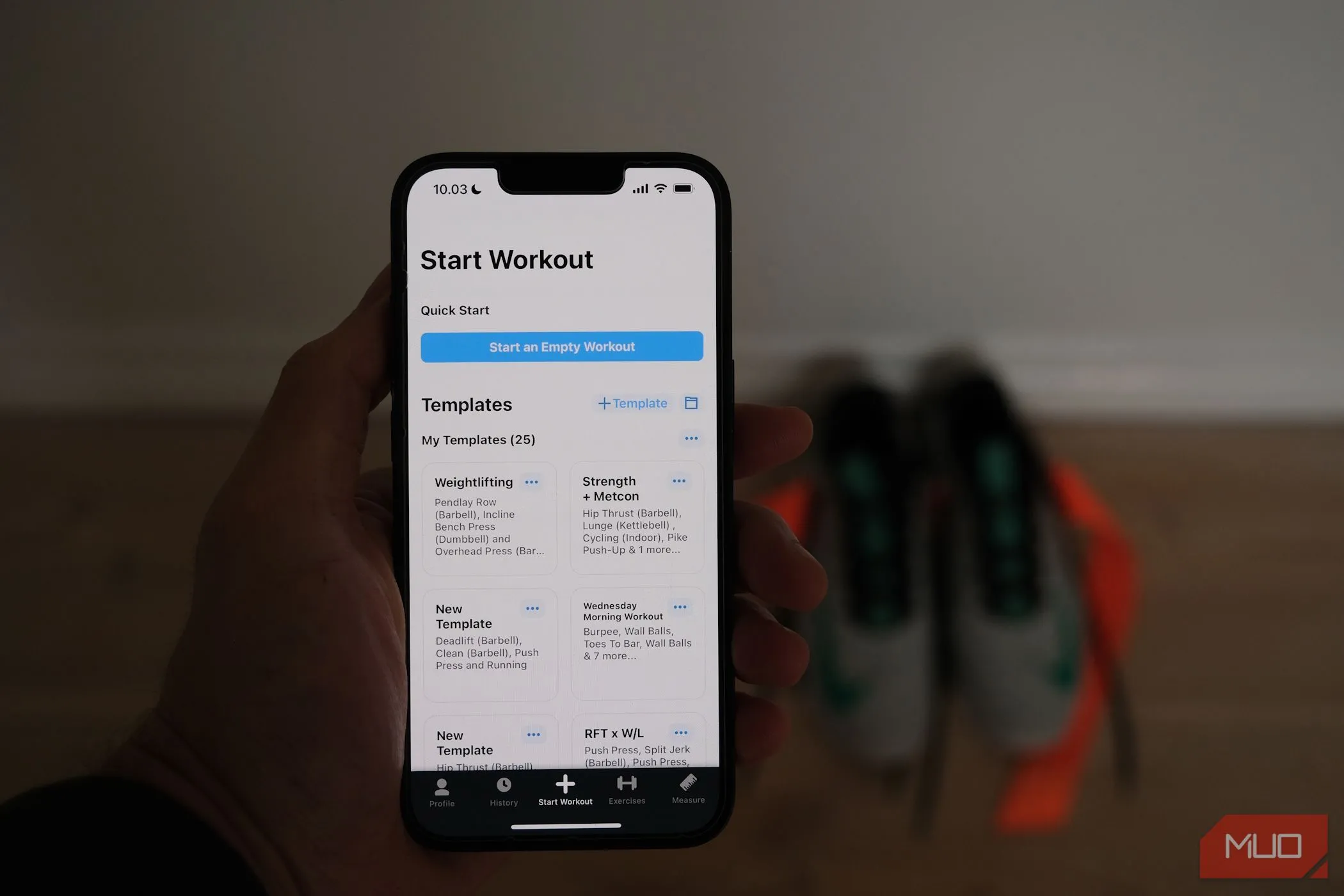 Điện thoại iPhone hiển thị ứng dụng theo dõi tập luyện với đôi giày chạy bộ ở hậu cảnh, nhấn mạnh tầm quan trọng của vận động thể chất