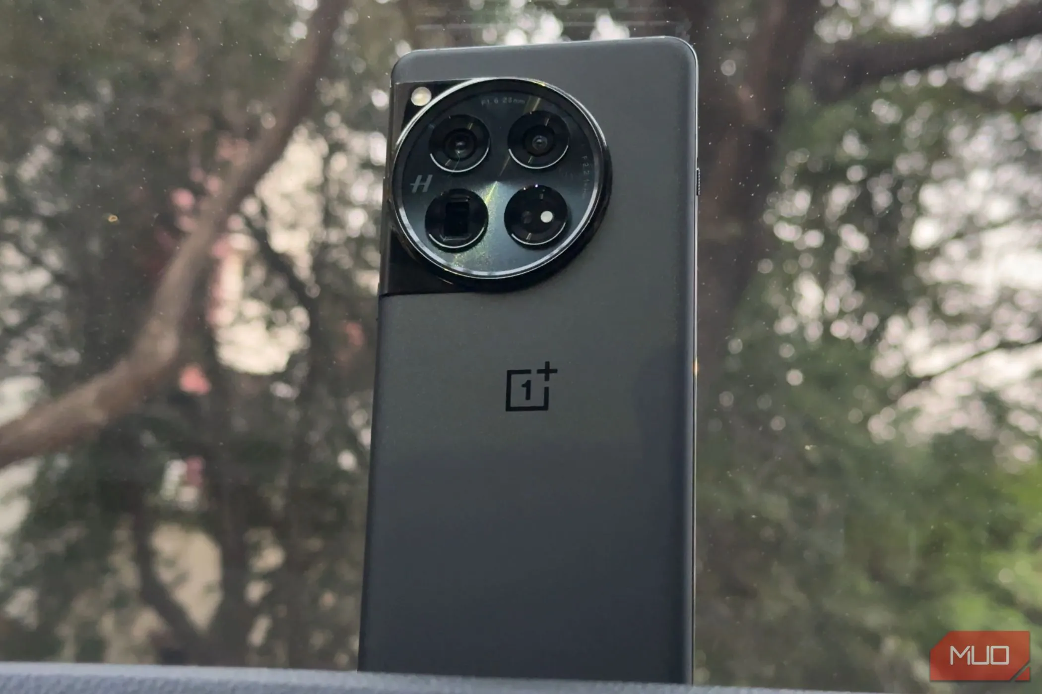Điện thoại OnePlus 12 màu đen được đặt trên bảng điều khiển xe hơi, minh chứng cho thiết kế vẫn còn rất cao cấp