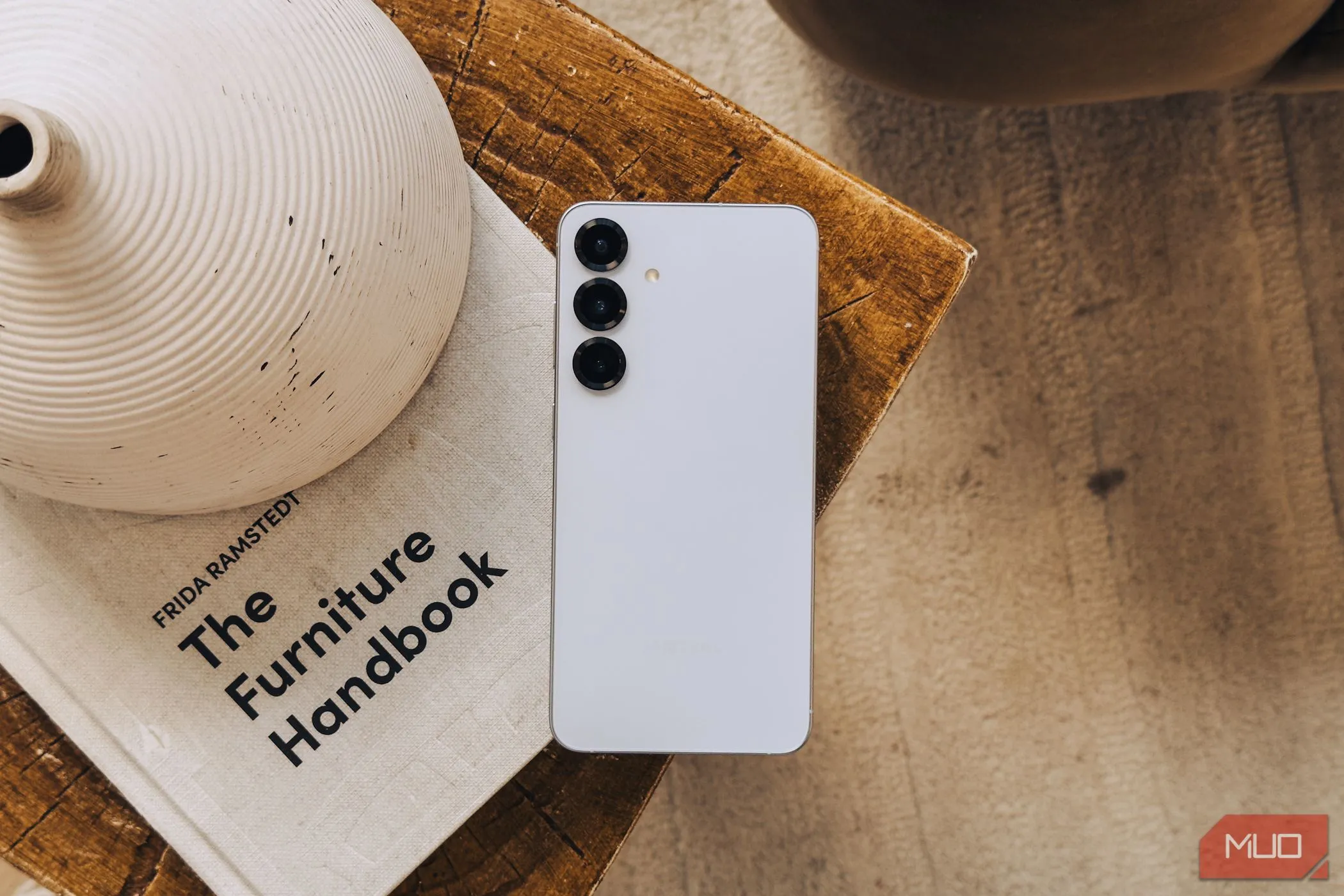 Điện thoại Samsung Galaxy S25 màu bạc đặt trên cuốn sách trắng, thể hiện thiết kế và cụm camera