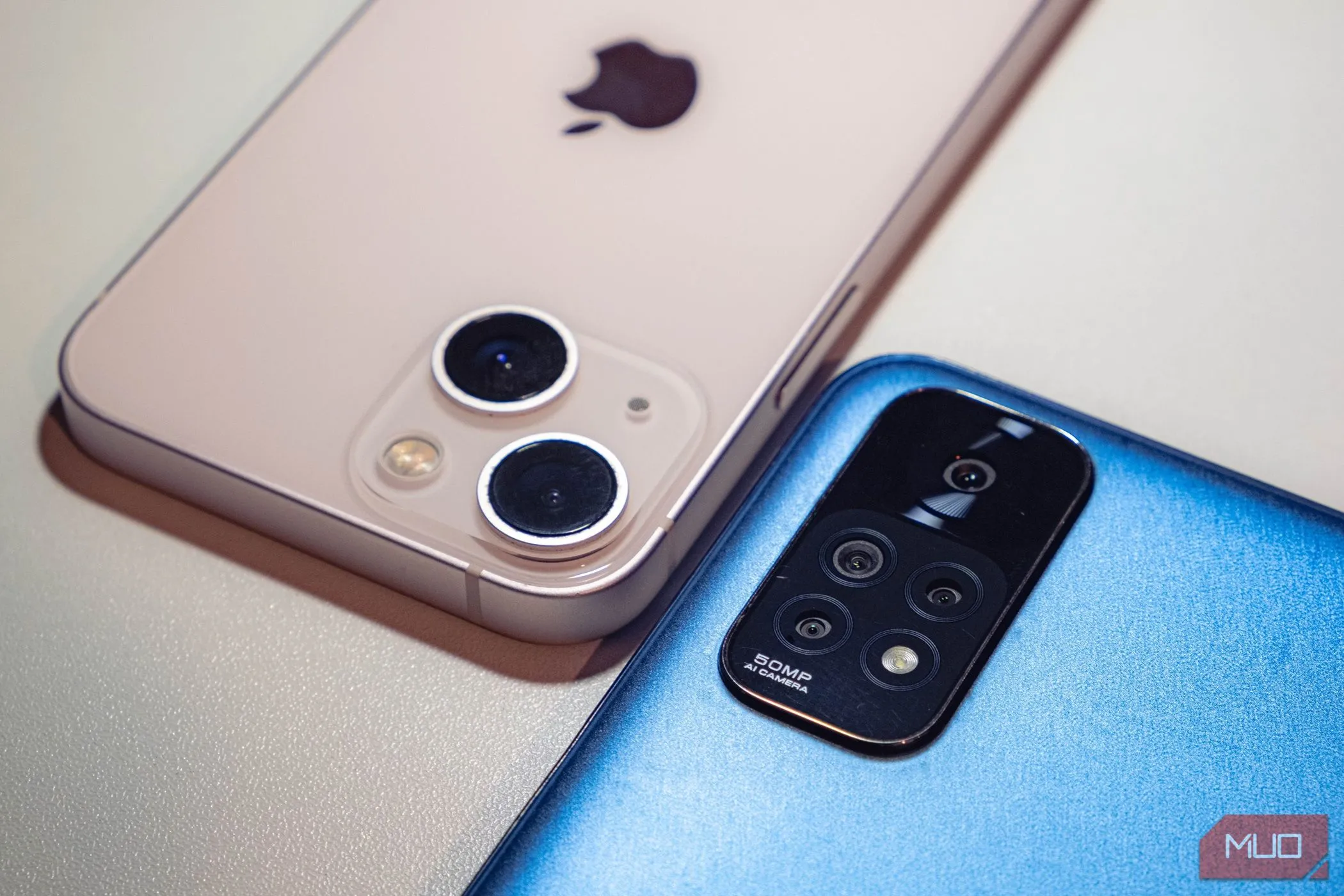 Hai chiếc điện thoại smartphone tầm trung màu xanh và hồng đặt úp, tượng trưng cho sự đa dạng và khả năng của phân khúc điện thoại giá phải chăng hiện nay.