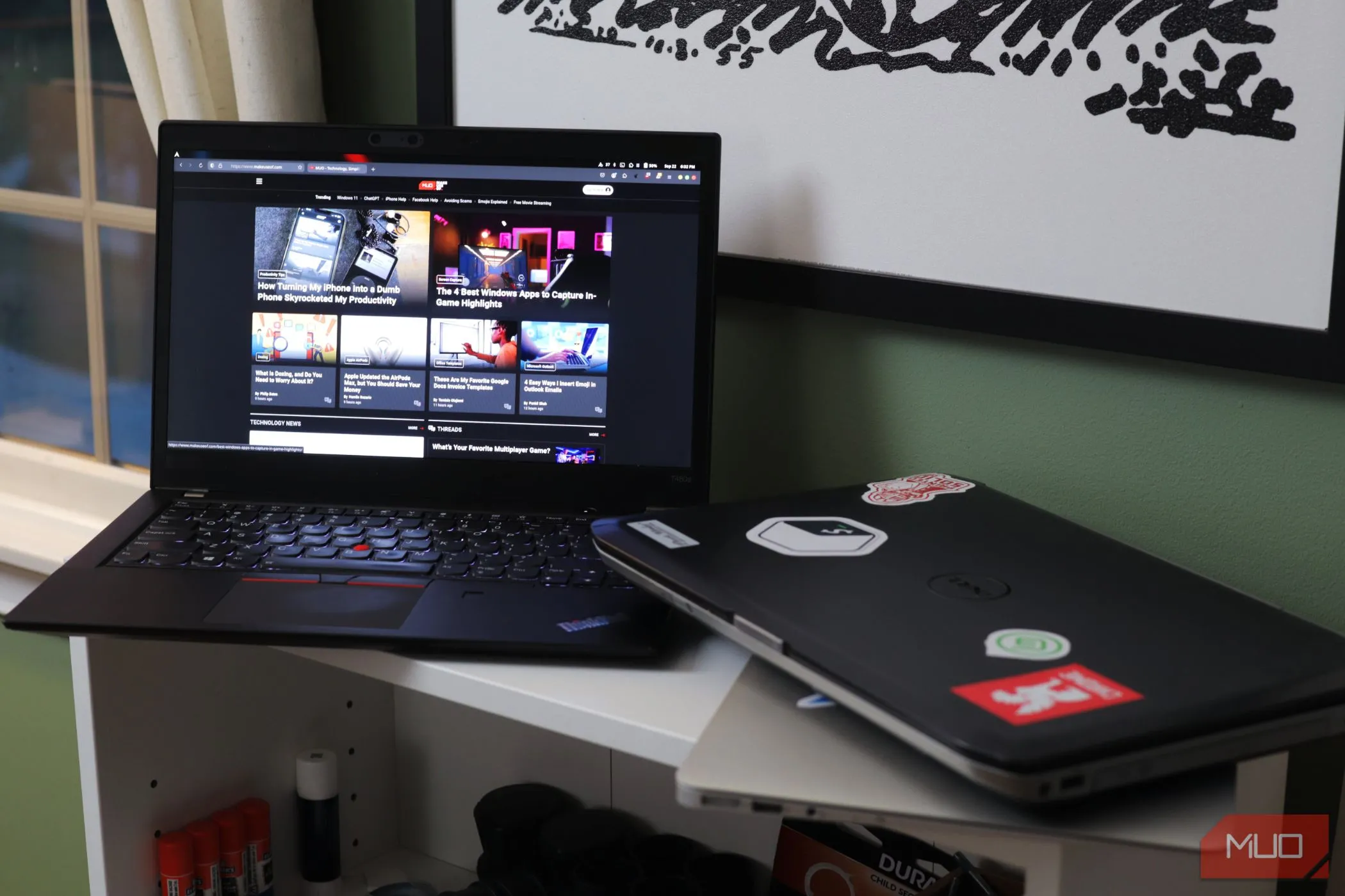 Hai chiếc laptop đặt trên kệ trắng, một chiếc đang mở, tượng trưng cho việc chia sẻ thiết bị và nguy cơ bảo mật mật khẩu trình duyệt.