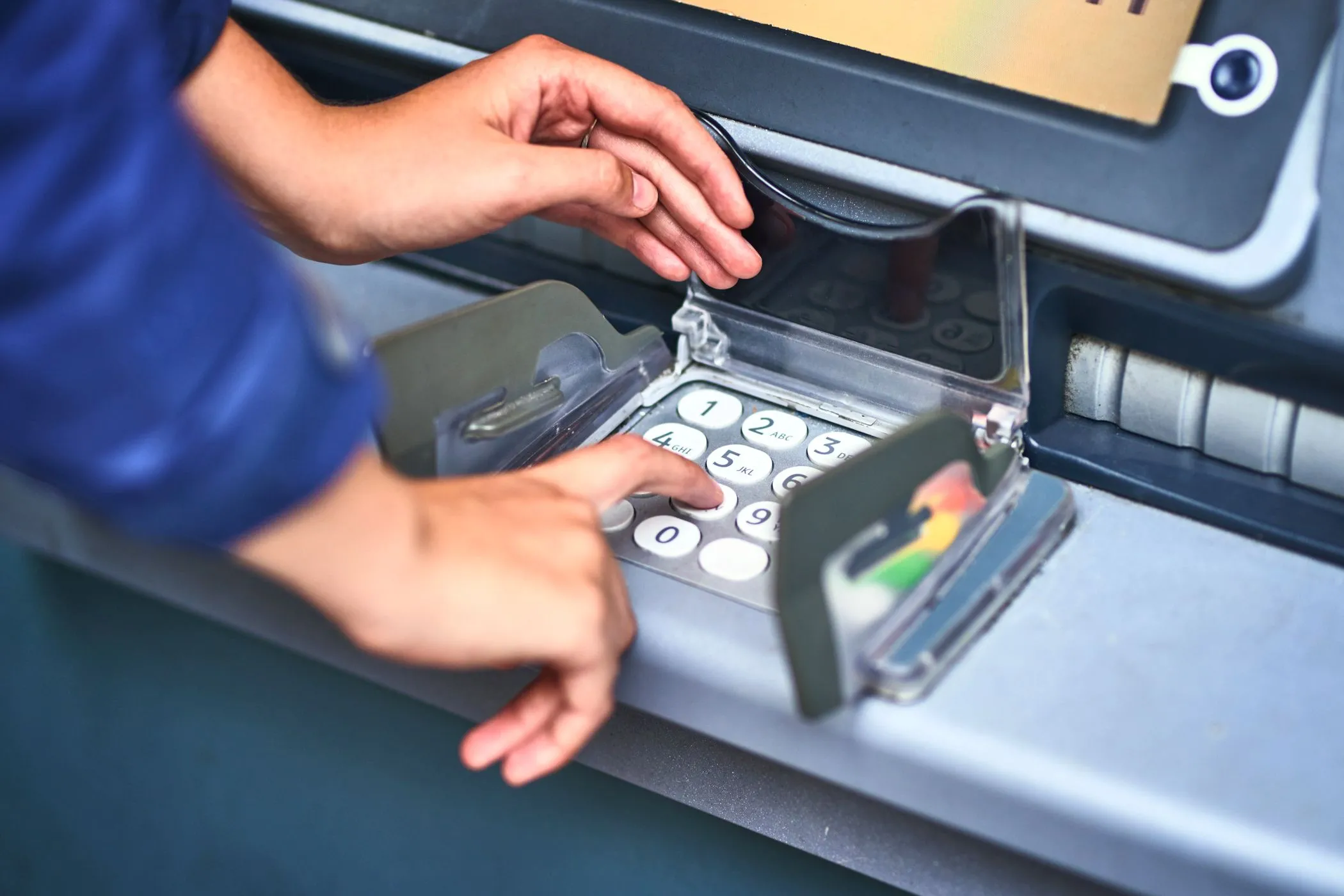 Hình ảnh người dùng đang nhập mã PIN trên bàn phím máy ATM, cần kiểm tra kỹ để phát hiện thiết bị skimmer