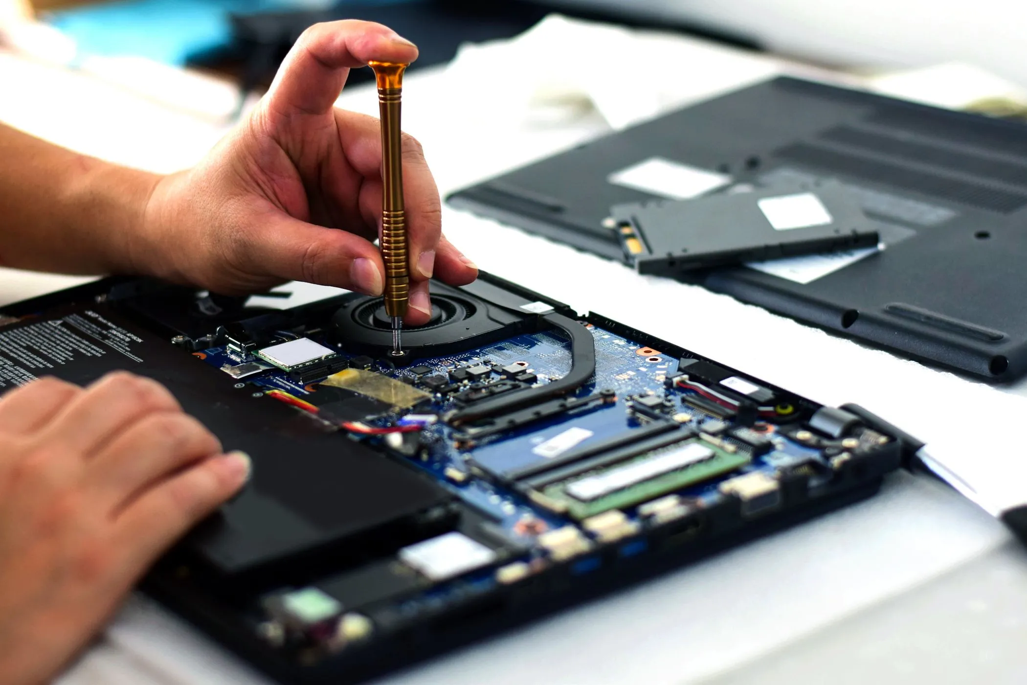 Kỹ thuật viên đang kiểm tra bo mạch chủ laptop, tượng trưng cho khó khăn trong việc sửa chữa linh kiện hàn chết trên máy mỏng.