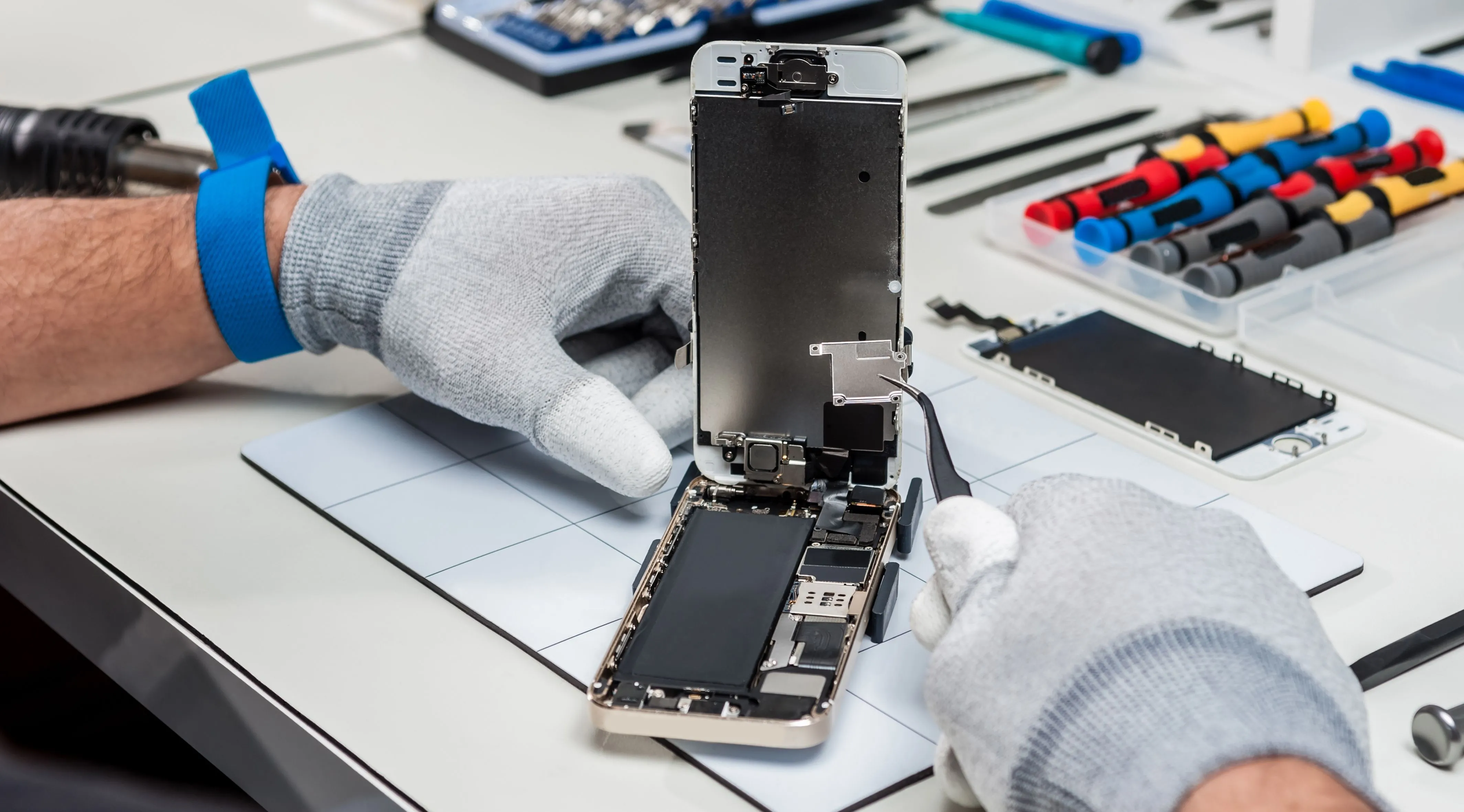 Kỹ thuật viên đang thực hiện sửa chữa trên bo mạch chủ của smartphone, minh họa phương pháp sửa đổi phần cứng để vô hiệu hóa tính năng theo dõi.