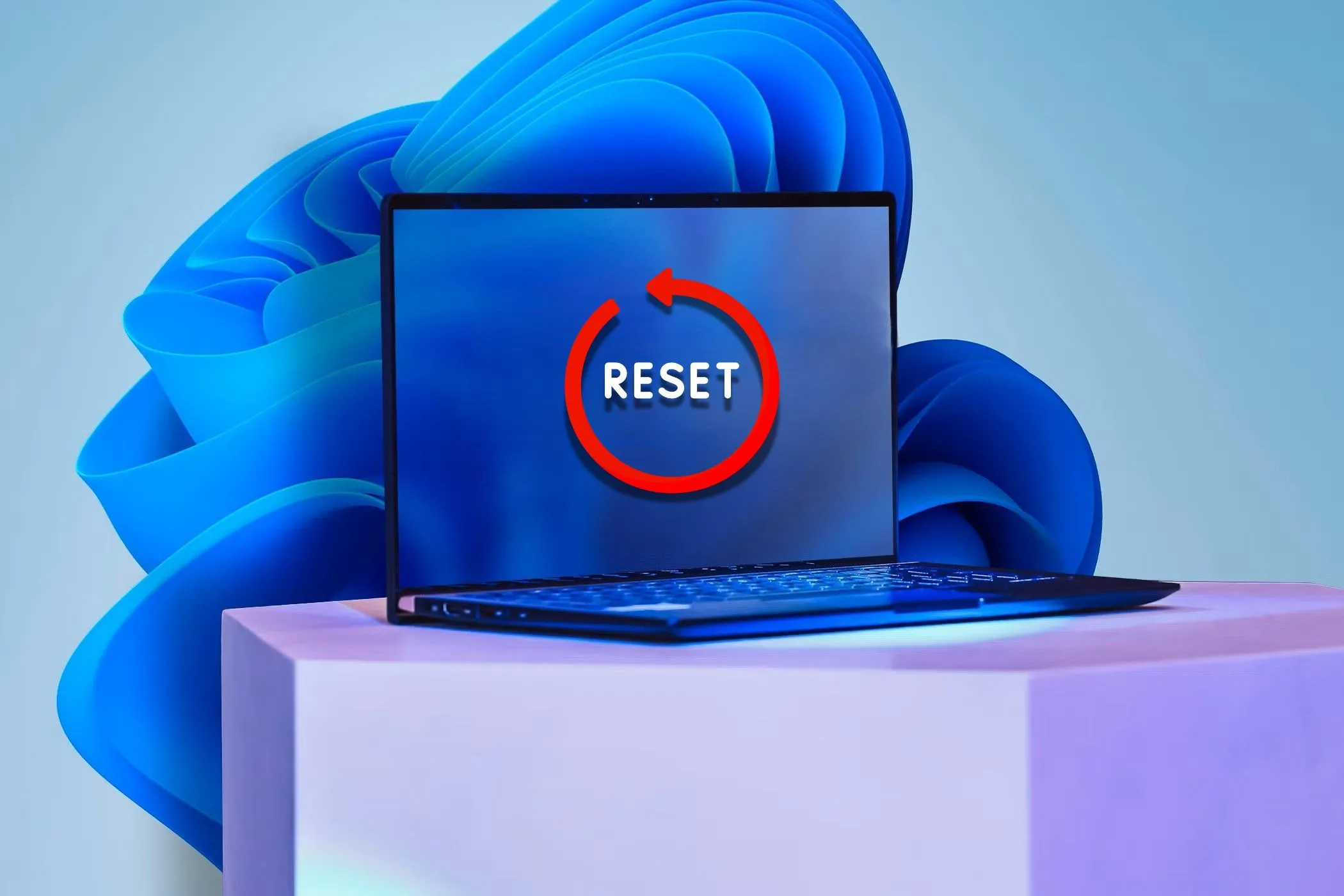 Laptop với nhãn dán &quot;Reset&quot; trên màn hình và hình nền Windows 11 ở phía sau