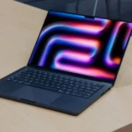 MacBook Pro với chip Apple Silicon thế hệ mới trên bàn gỗ, màn hình hiển thị macOS 26