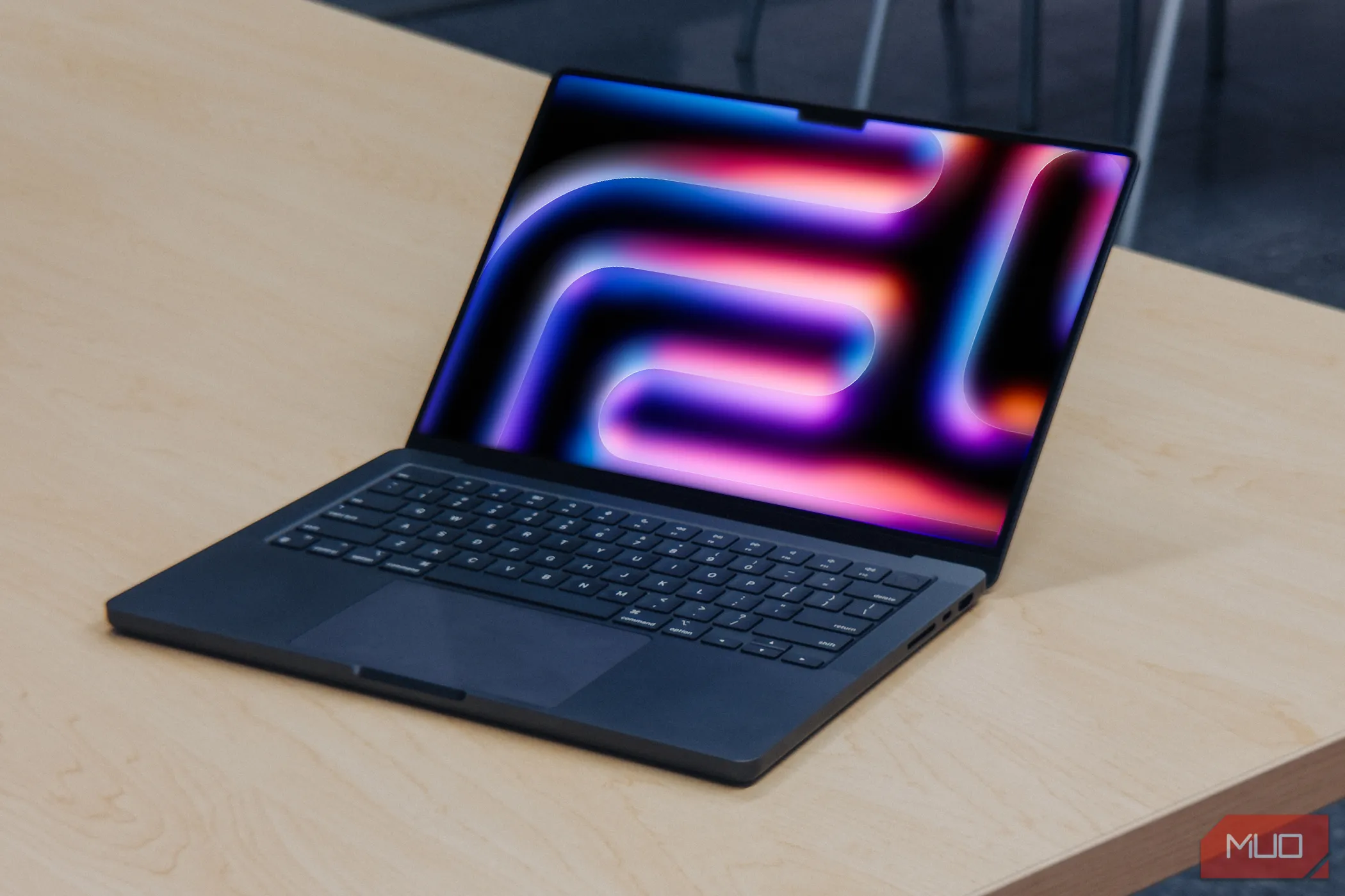 MacBook Pro với chip Apple Silicon thế hệ mới trên bàn gỗ, màn hình hiển thị macOS 26