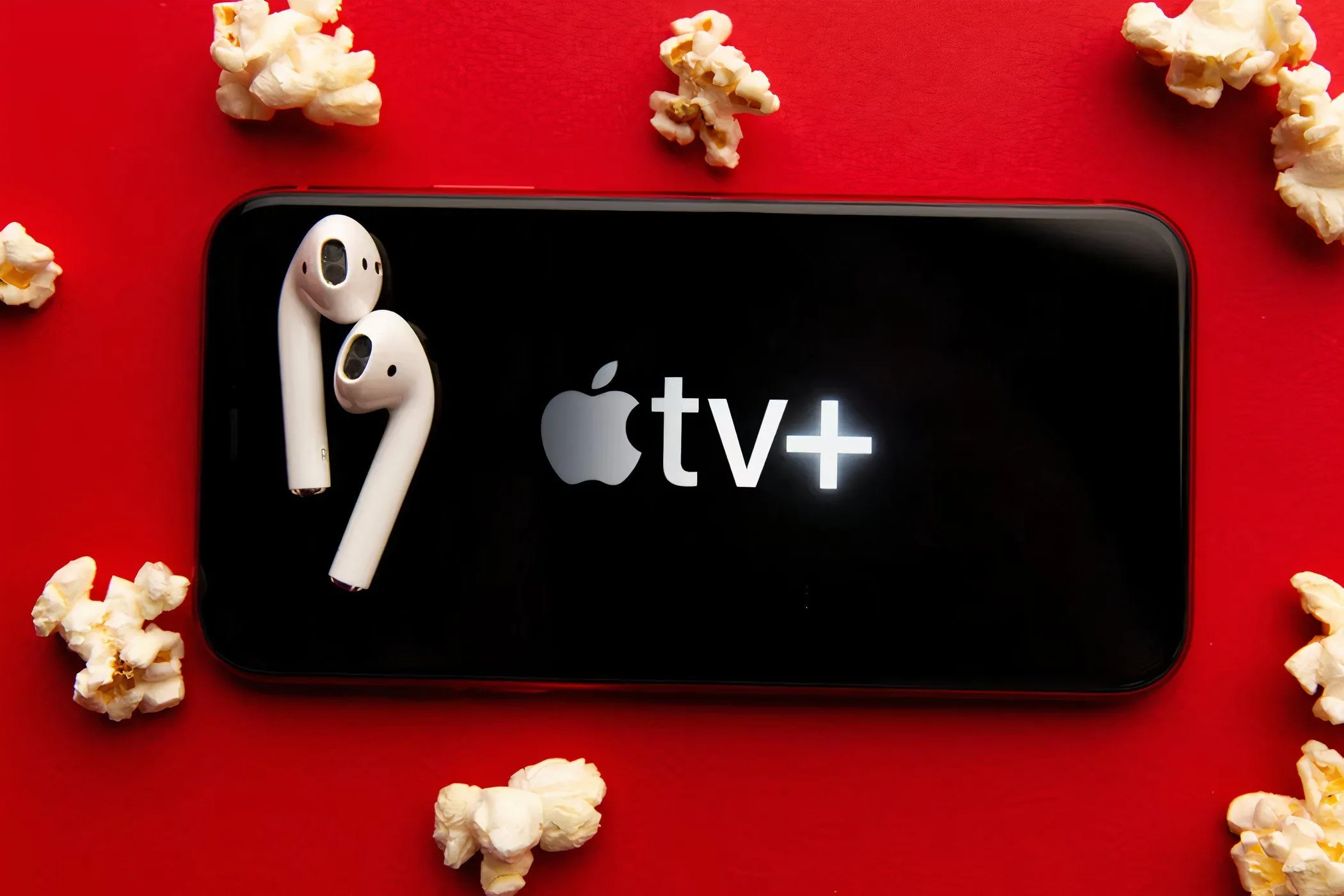 Màn hình điện thoại hiển thị logo Apple TV+ với bắp rang bơ và tai nghe, minh họa trải nghiệm giải trí di động tiện lợi