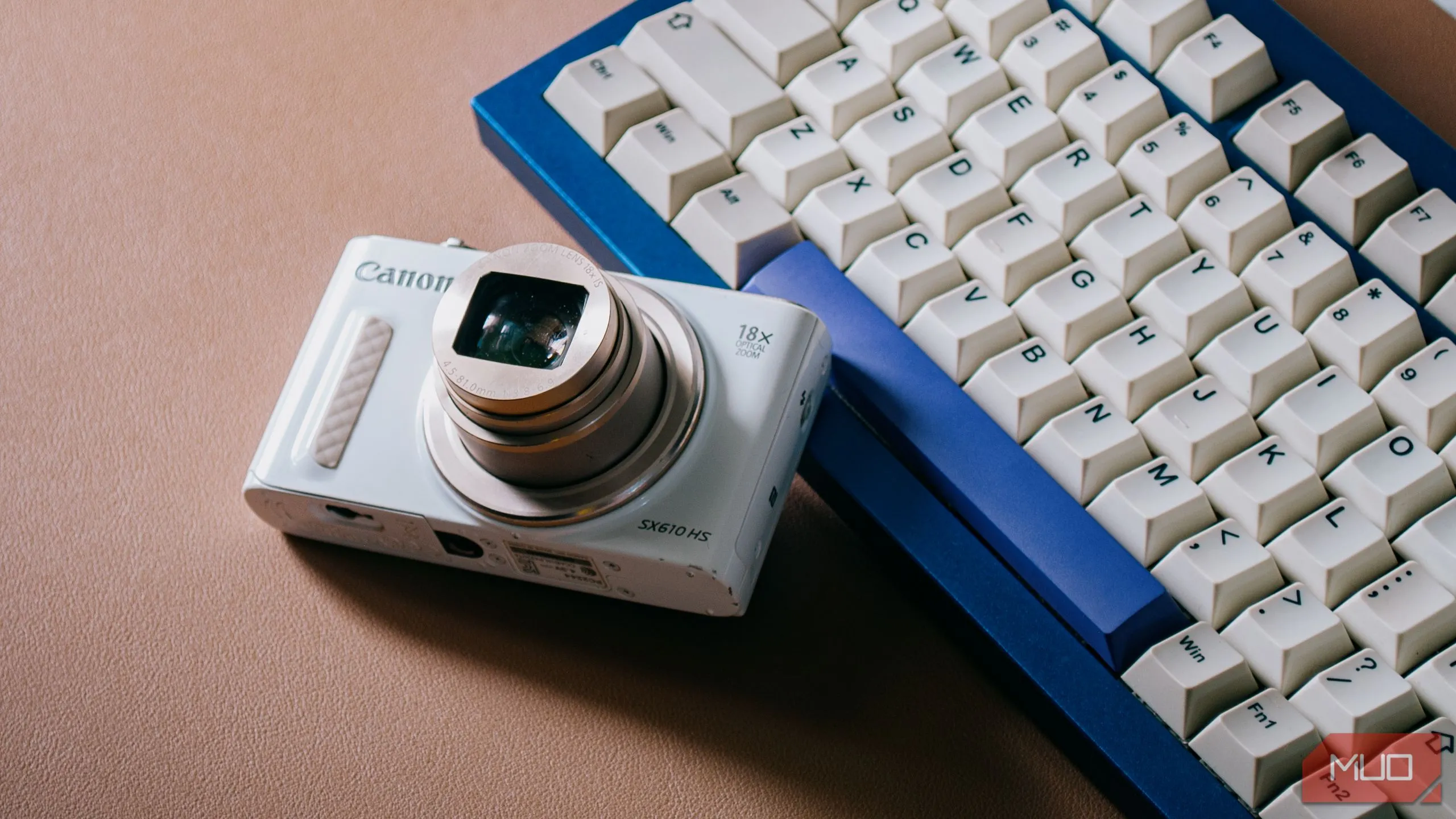Máy ảnh digicam đang mở ống kính đặt trên bàn phím