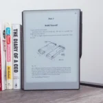 Máy tính bảng reMarkable Paper Pro đặt cạnh sách trên bàn gỗ, thể hiện kích thước và trải nghiệm đọc sách.
