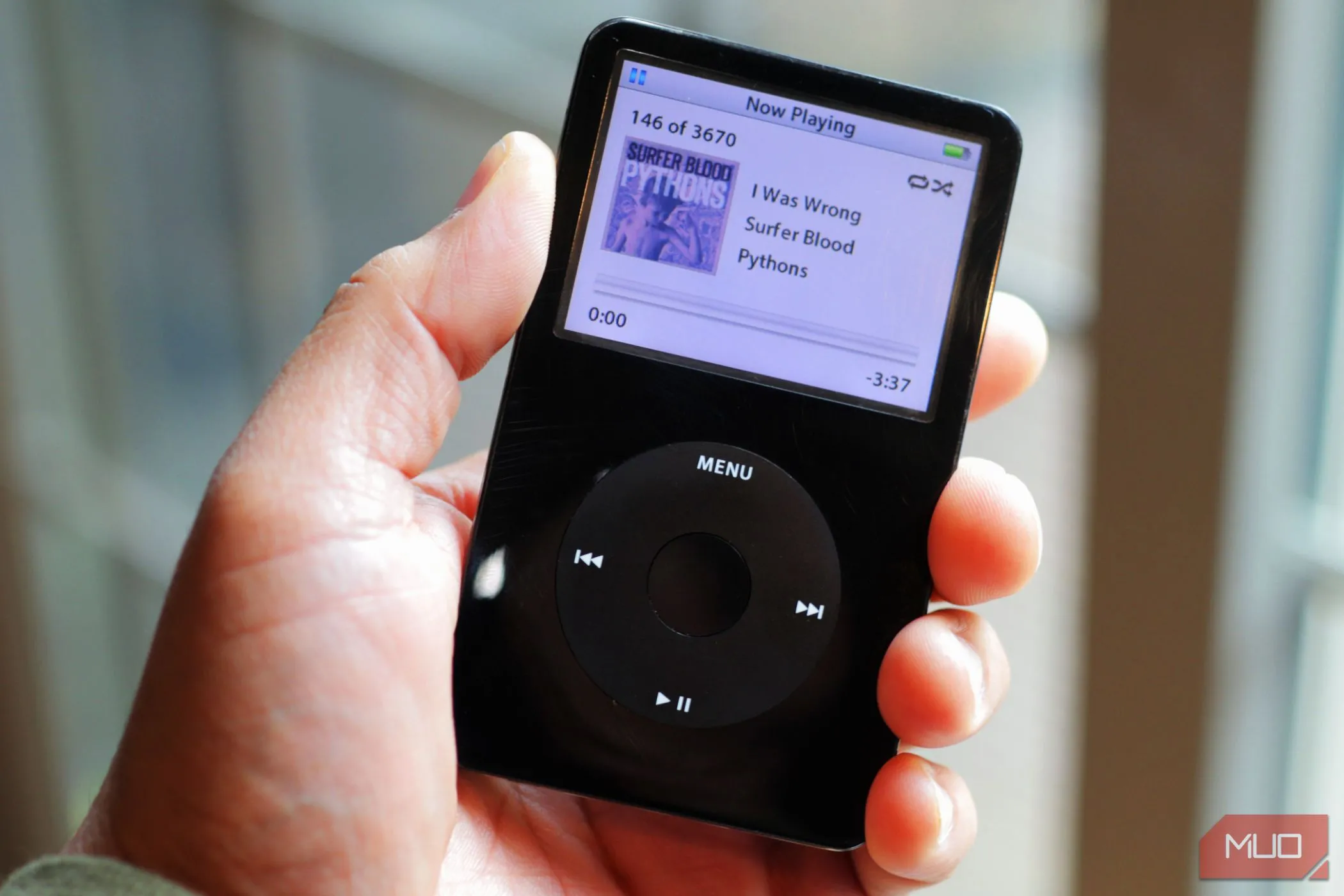 Một chiếc iPod Classic màu đen đang được cầm trên tay, biểu tượng của kỷ nguyên máy nghe nhạc MP3 chuyên dụng trước khi các dịch vụ streaming nhạc trên smartphone phổ biến.