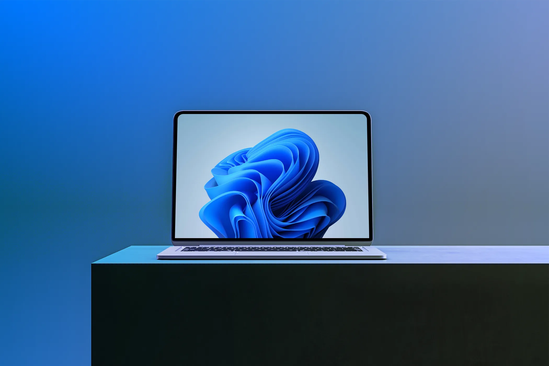 Một chiếc laptop hiển thị hình nền Windows 11 trên bề mặt tối