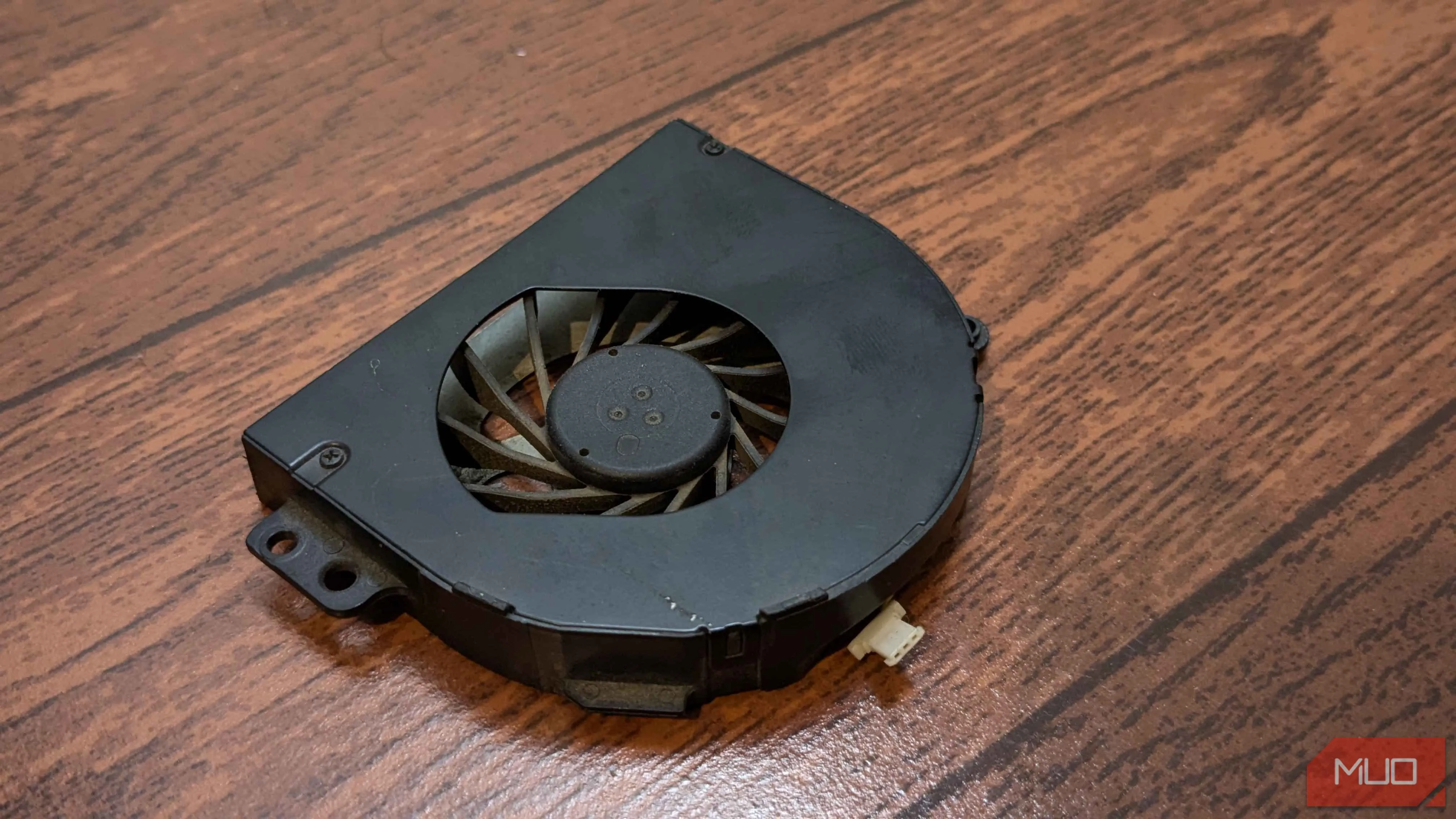Một chiếc quạt tản nhiệt laptop riêng lẻ nằm trên bàn, biểu tượng cho linh kiện cần thay thế khi quạt cũ bị hỏng hoặc phát ra tiếng ồn bất thường do lỗi ổ bi