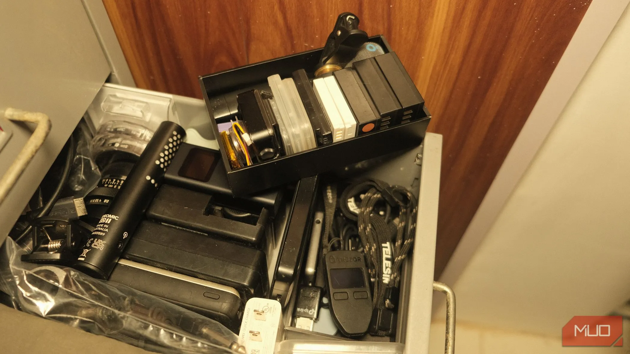 Một ngăn bí mật nằm bên dưới hộp pin máy ảnh, chứa ví lạnh Trezor và các loại cáp ngắn ít dùng, giúp tối ưu không gian lưu trữ và bảo mật