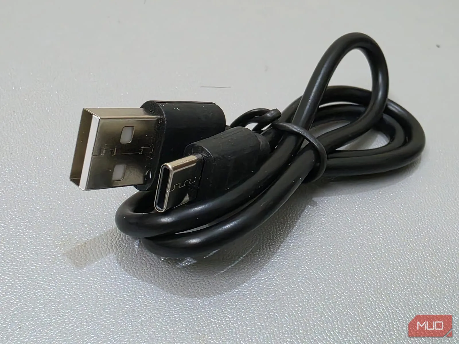 Một sợi cáp sạc USB-A màu đen có dấu hiệu cũ kỹ và rẻ tiền, biểu trưng cho cáp kém chất lượng