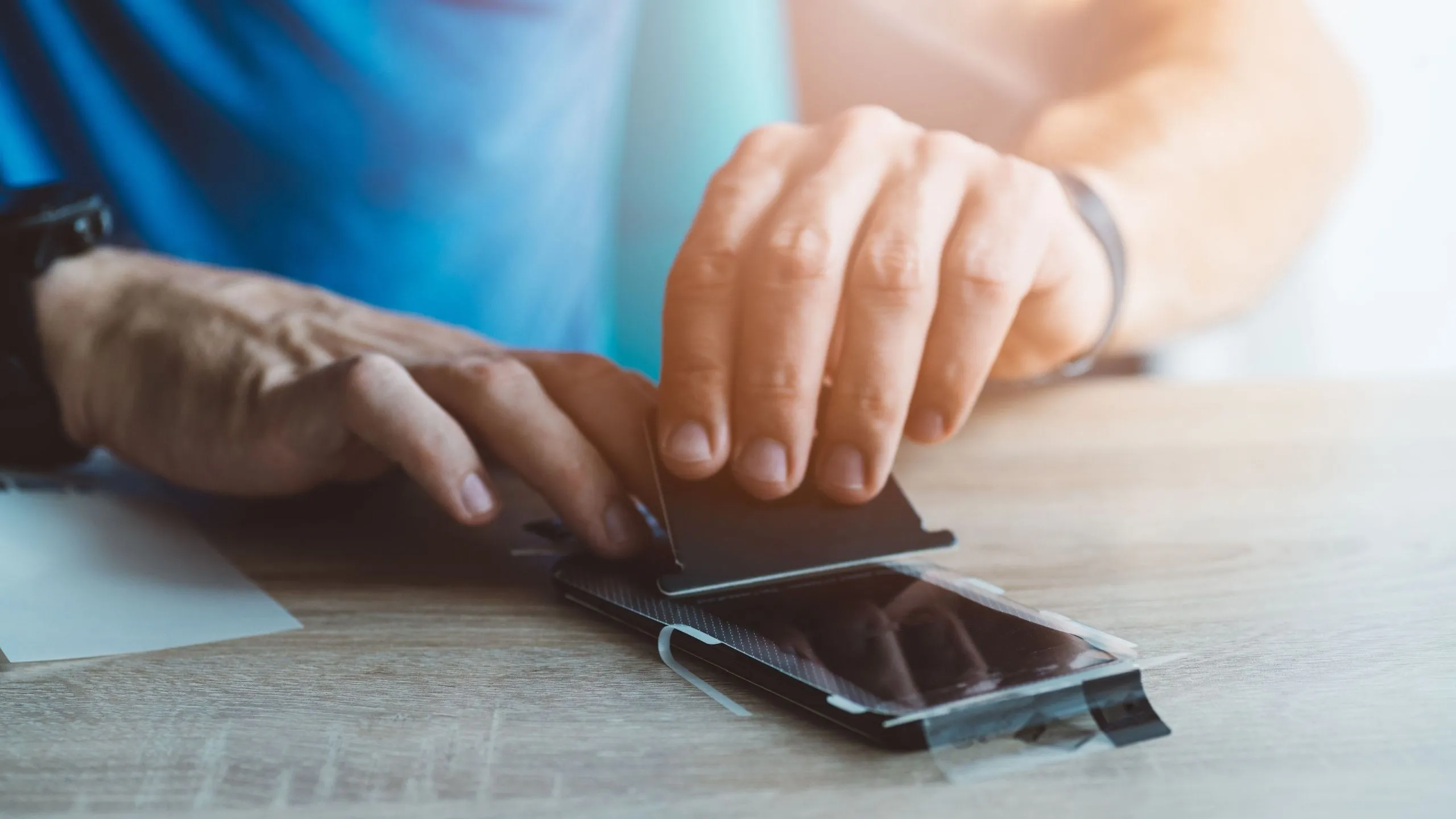 Người đàn ông đang dán miếng bảo vệ màn hình điện thoại, minh họa cho miếng dán kháng khuẩn iPhone không hiệu quả.