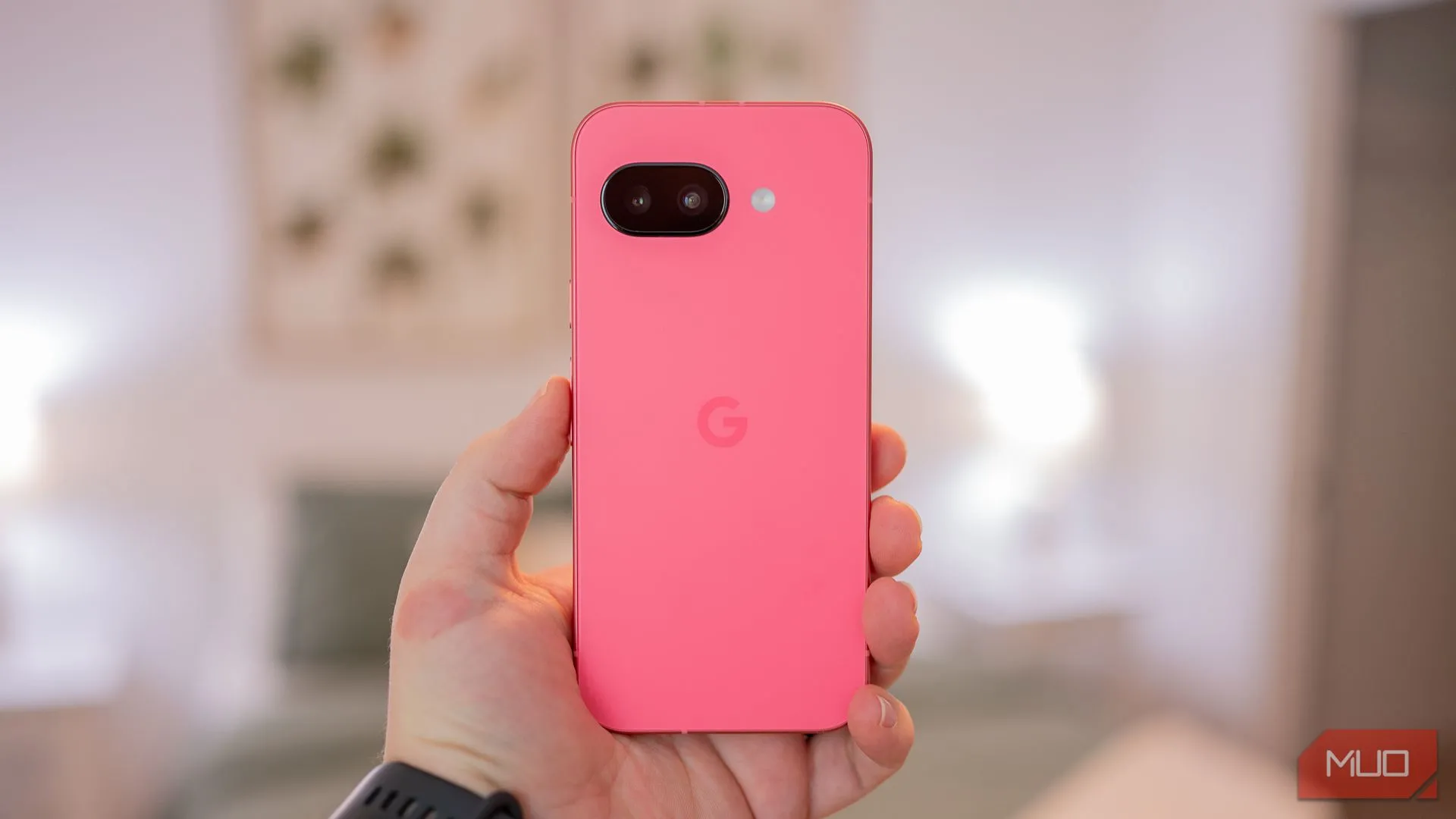 Người dùng cầm điện thoại Google Pixel 9a với mặt lưng kính mờ và khung kim loại thể hiện thiết kế tối giản