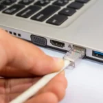 Người dùng đang cắm cáp mạng Ethernet vào máy tính xách tay Windows
