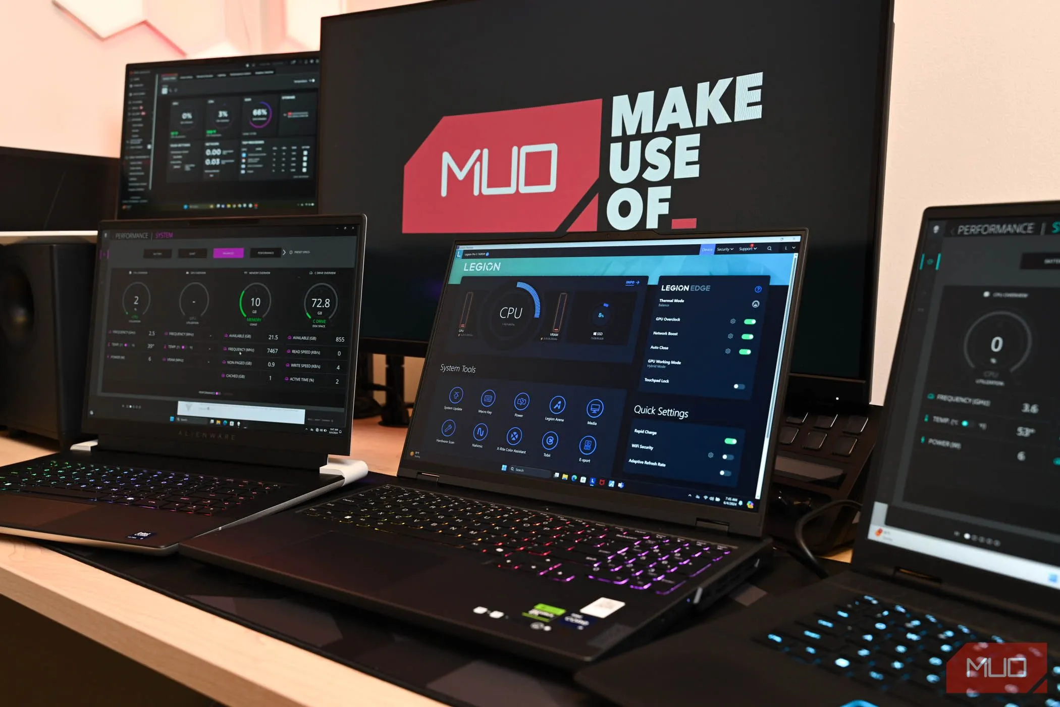 Người dùng đang kiểm tra laptop gaming trước màn hình lớn có logo MakeUseOf, thể hiện sự phân tâm khi có nhiều hiển thị.