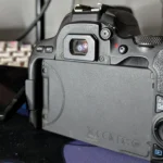 Người dùng nhìn qua kính ngắm quang học của máy ảnh Canon 200D, minh họa lợi thế về độ chính xác và không độ trễ của DSLR