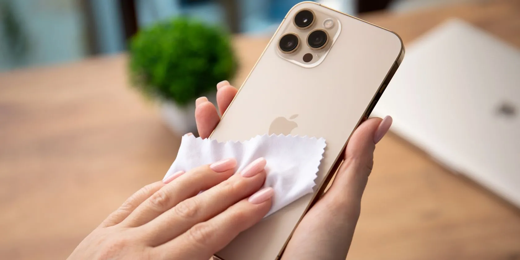 Người phụ nữ đang vệ sinh màn hình iPhone bằng khăn microfiber, cách làm hiệu quả hơn các bộ vệ sinh &quot;cao cấp&quot; lãng phí.