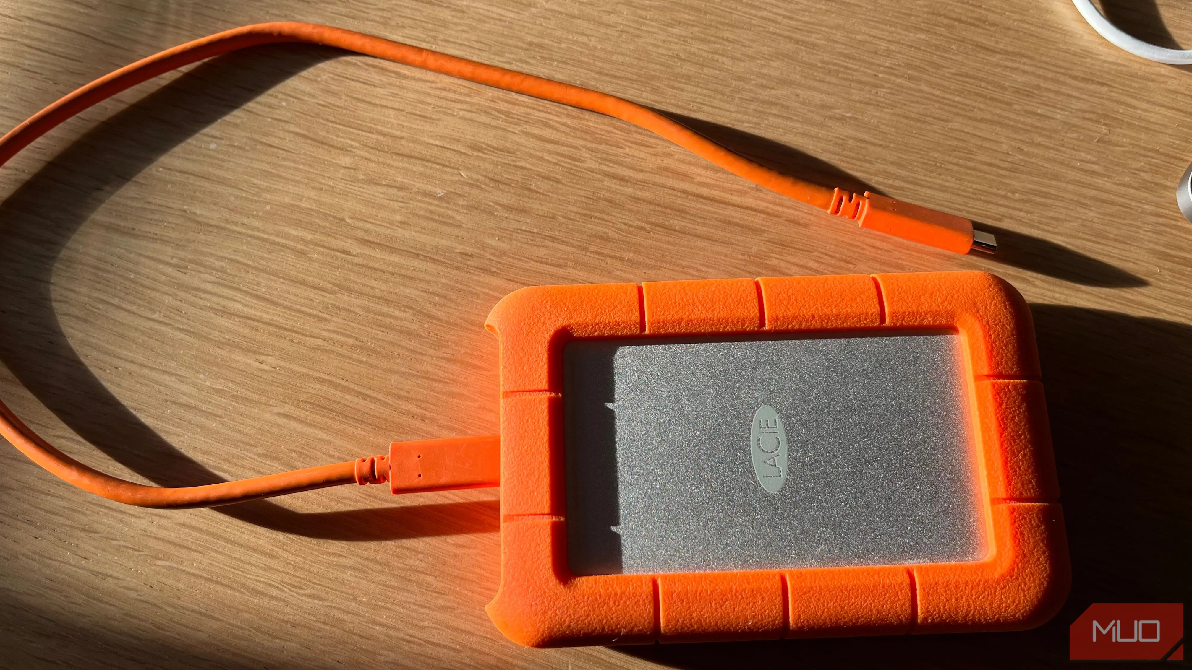 Ổ cứng di động LaCie Rugged màu cam, nhấn mạnh độ bền và khả năng lưu trữ dữ liệu lớn cho các tệp công việc.