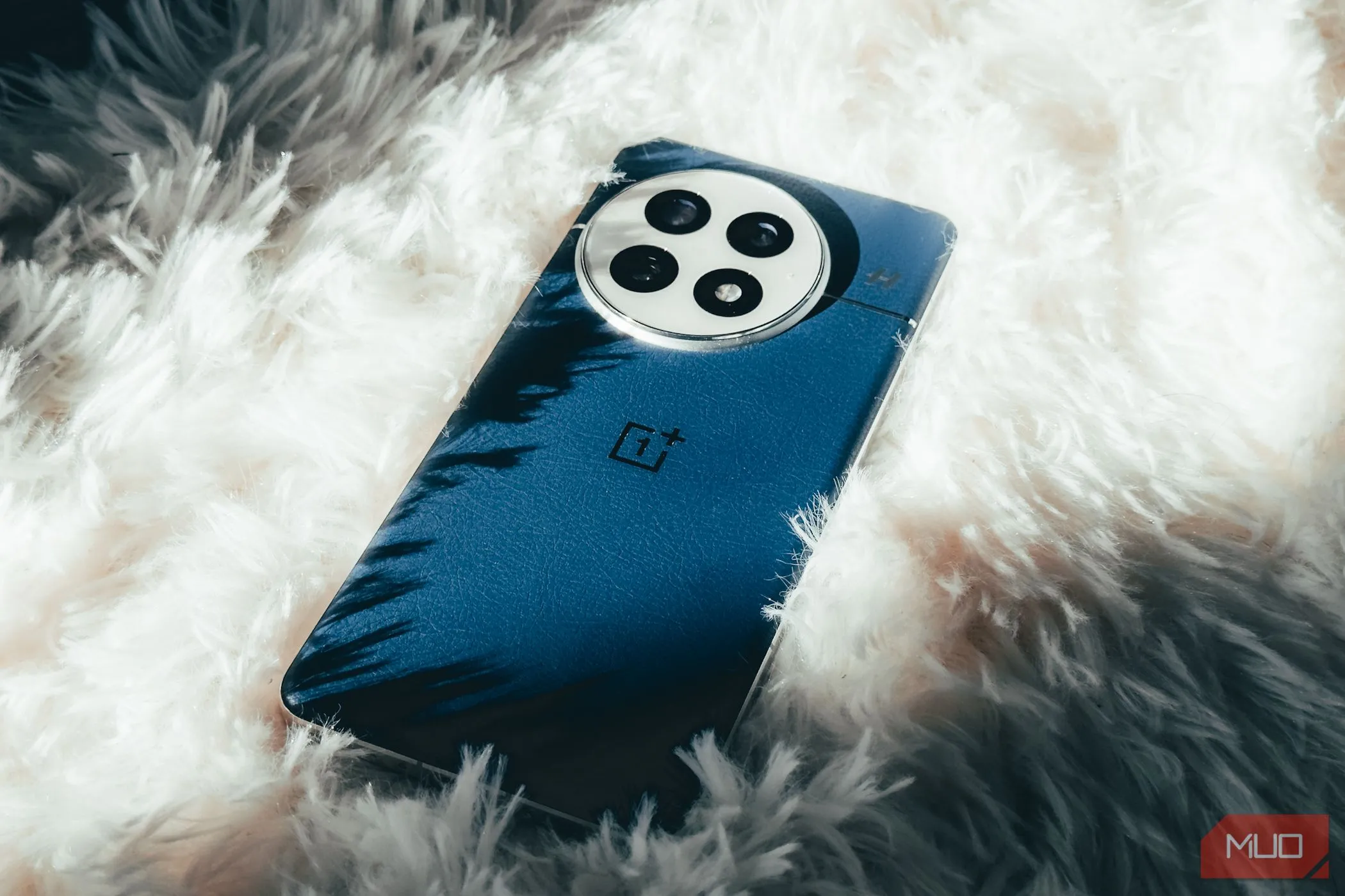 OnePlus 13 Midnight Ocean với mặt lưng da vegan trên nền thảm trắng.
