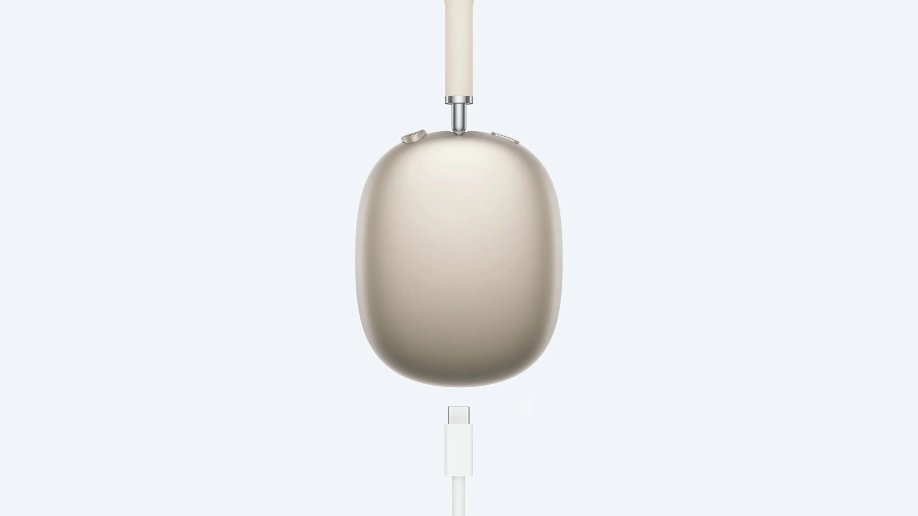 Tai nghe AirPods Max màu Starlight đang được sạc bằng cáp USB-C, minh họa việc không thể sử dụng khi sạc
