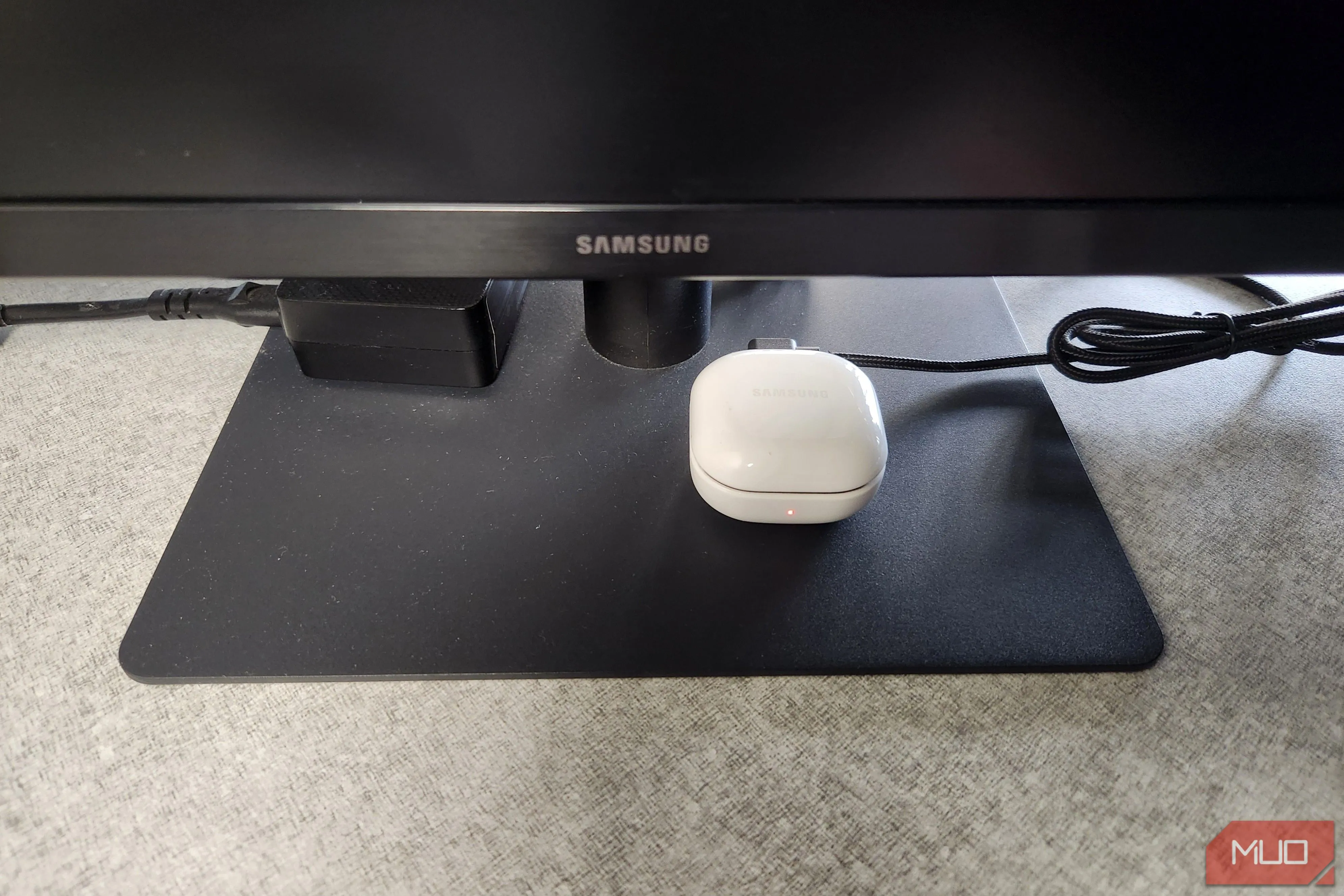 Tai nghe Bluetooth đang sạc qua cổng USB trên màn hình máy tính, minh họa khả năng sạc thiết bị nhỏ.