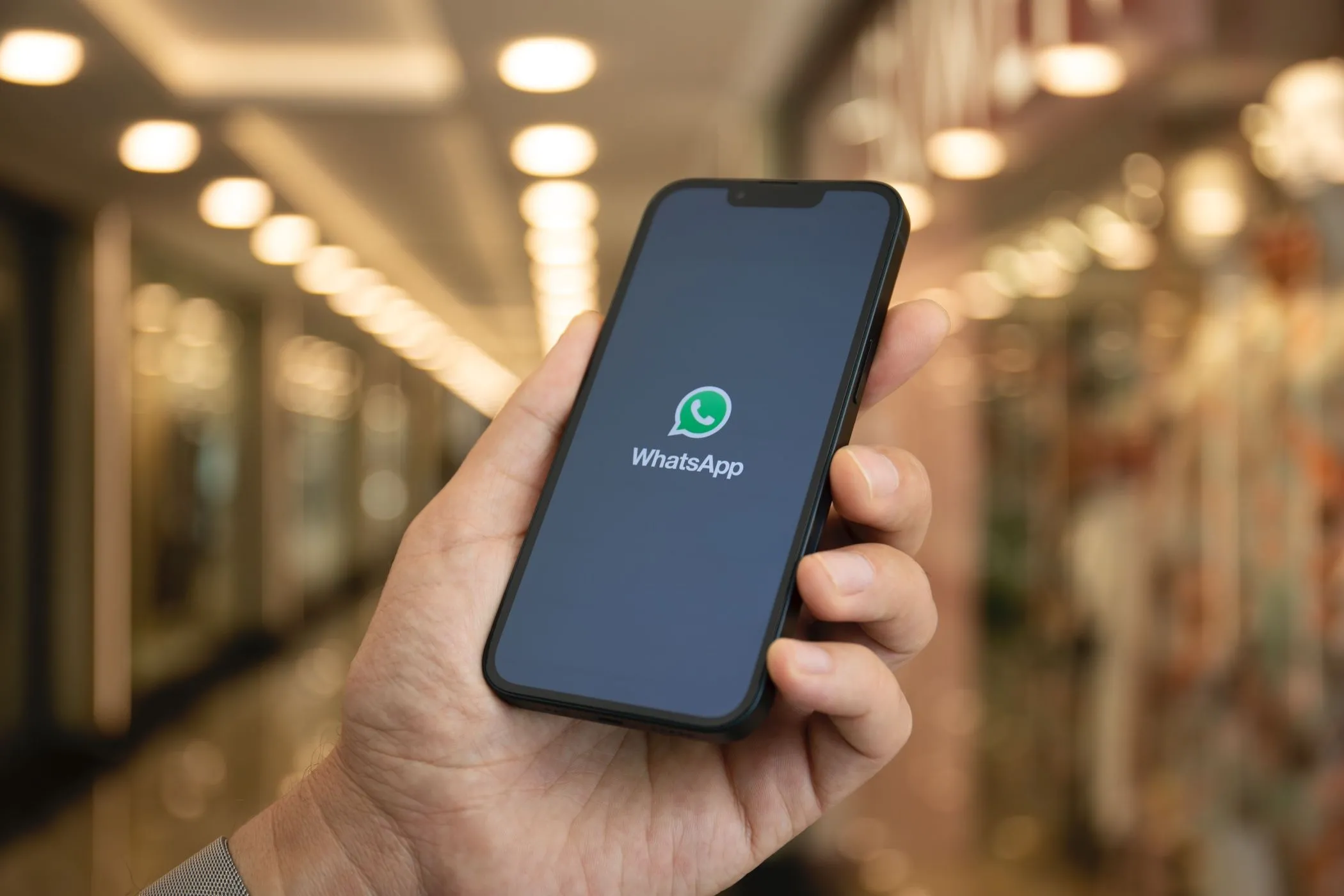 Tay cầm điện thoại hiển thị logo WhatsApp, minh họa tính năng mới của ứng dụng