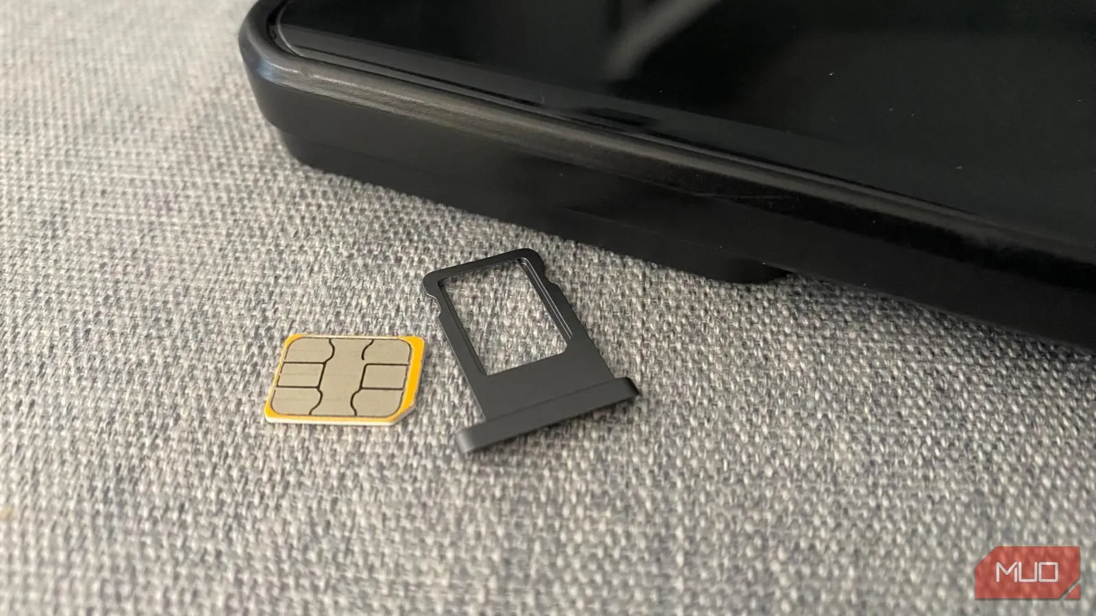 Thẻ SIM vật lý và khay đựng đặt cạnh điện thoại di động, tượng trưng cho lựa chọn SIM truyền thống.