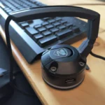 Thiết bị kẹp dây chuột (mouse bungee) màu đen đặt trên bàn làm việc bằng gỗ