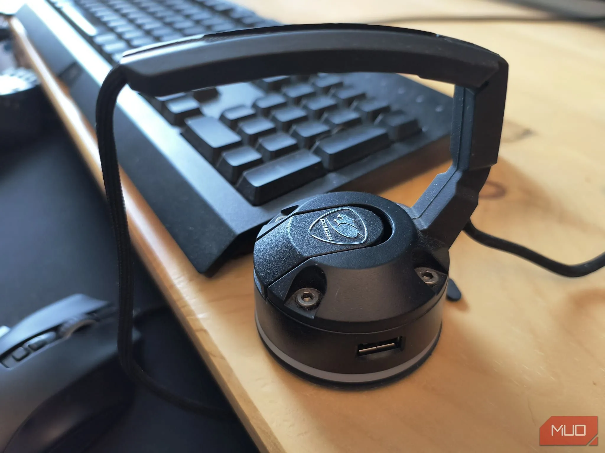 Thiết bị kẹp dây chuột (mouse bungee) màu đen đặt trên bàn làm việc bằng gỗ