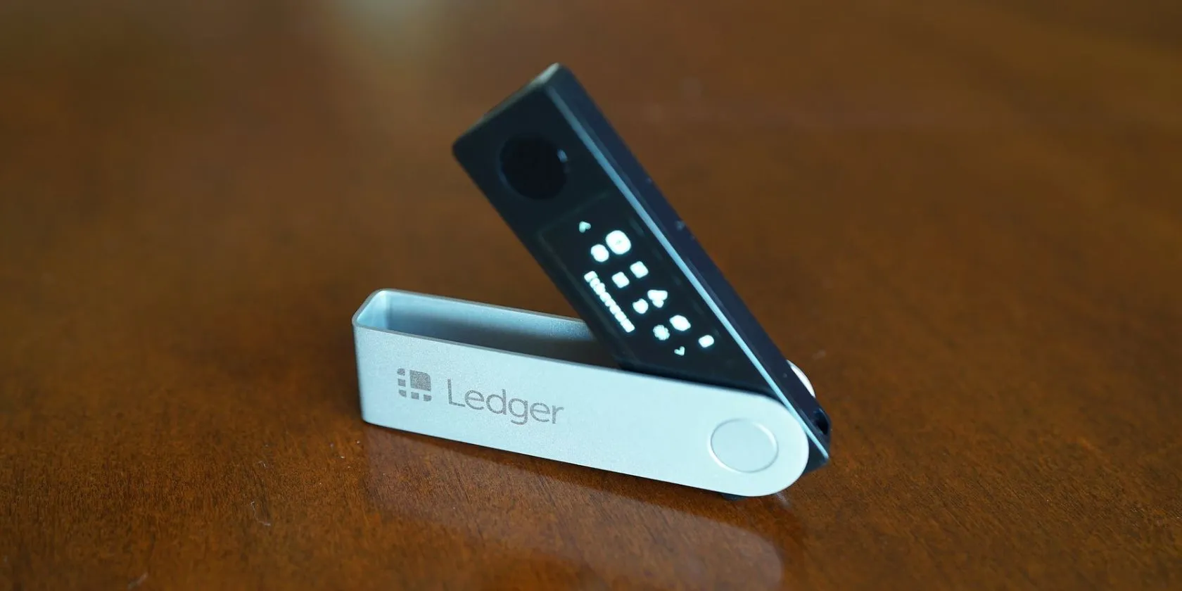 Thiết bị ví lạnh Ledger Nano X màu đen đặt trên bề mặt gỗ, tượng trưng cho an ninh tiền điện tử.